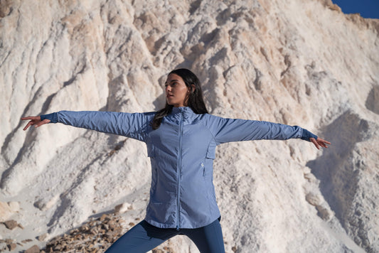 A woman practicing yoga in modest activewear by qynda, with a mountainous backdrop, embodying a sense of balance and tranquility in nature.