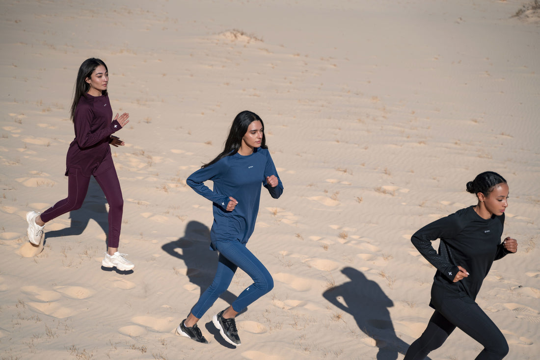 Three women jogging in the sand, casting long shadows in the soft light, clad in modest activewear by qynda.