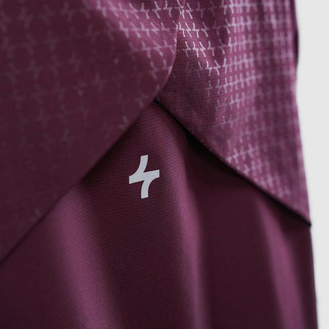 Close-up of cooldown coat by Qynda with a repetitive pattern featuring small white crosses and a single, prominent Qynda brand logo.