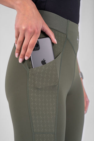 A person wearing high-waisted olive green modest active wear leggings with a phone tucked in the side pocket.