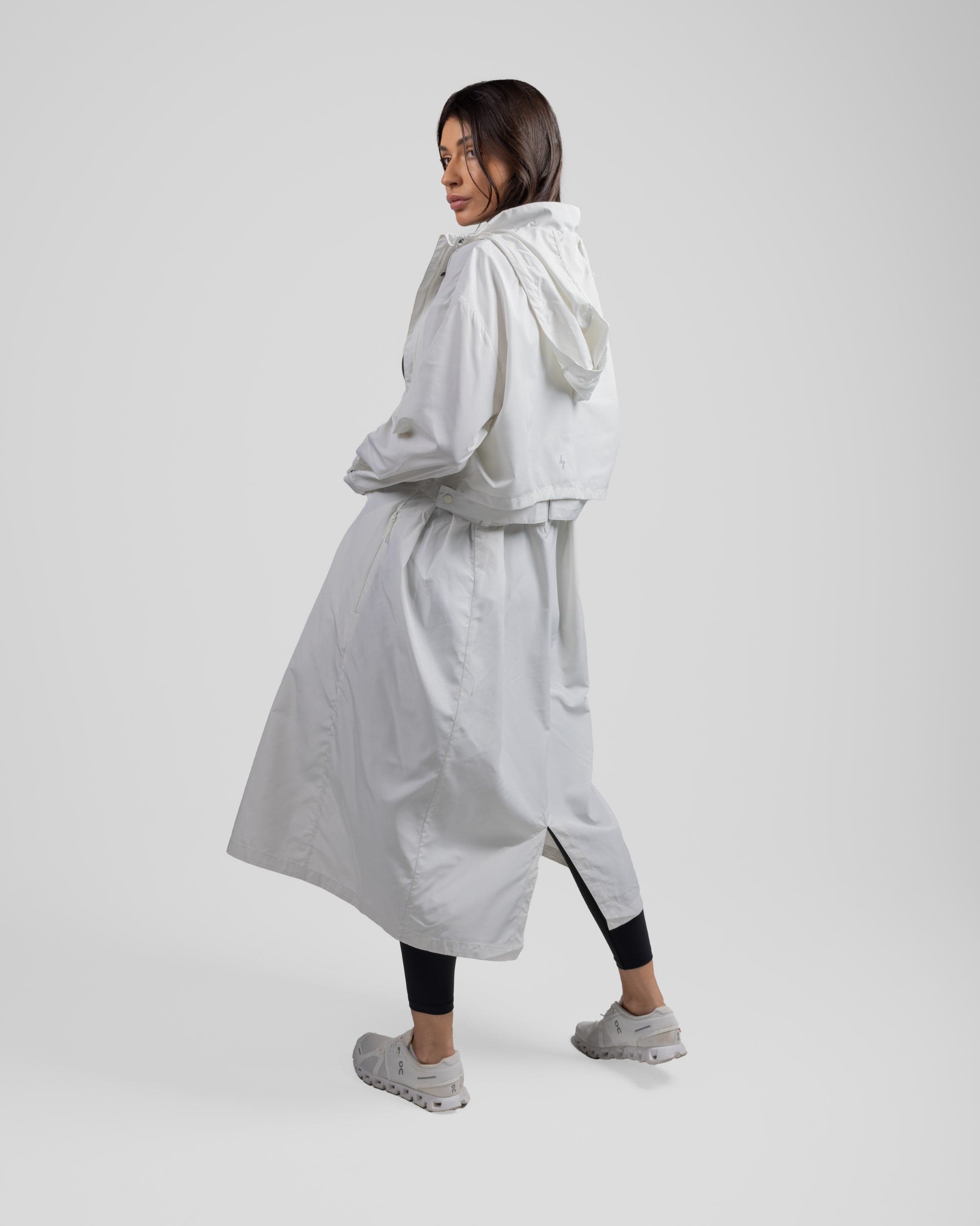A model viewed from behind, turns her head to her left, wearing a stylish modest Off White MAK LIGHT PARKA by Qynda.