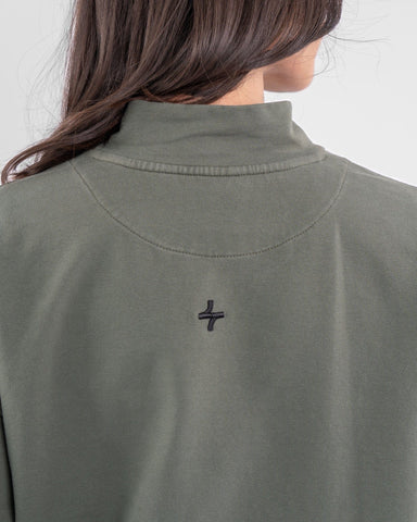 Close-up of the back of a woman's Olive REHAL SWEATER with a qynda logo embroidered near the neckline.