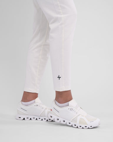 A woman standing in a relaxed pose, showcasing a pair of white sneakers with a unique sole pattern, wearing moisture-wicking cotton joggers, CANTARA PANTS by qynda.