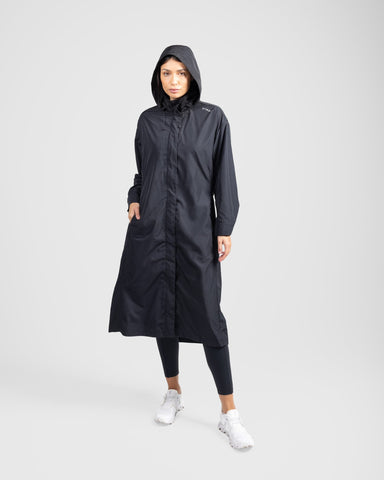 A model in a modest black MAK LIGHT PARKA by Qynda made of lightweight fabric and leggings, posing, standing against a light gray background.