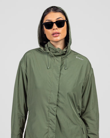 A model in a stylish olive green Modest MAK LIGHT PARKA made of lightweight fabric, with a hood, looking poised and confident.