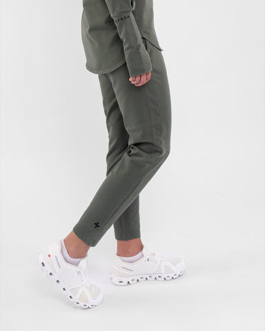 A close-up of a woman's lower legs clad in high-waisted, Olive CANTARA PANTS and white sneakers, highlighting modest sportswear of qynda.