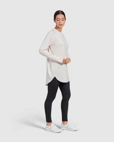 A model stands against a white background, dressed in a modest shell MOD LONG SLEEVE T-SHIRT and black leggings