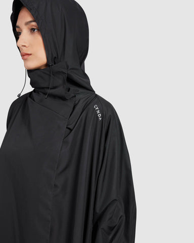 Woman wearing a super light fabric, sleek black hooded COOLDOWN coat with a subtle brand logo on the shoulder.
