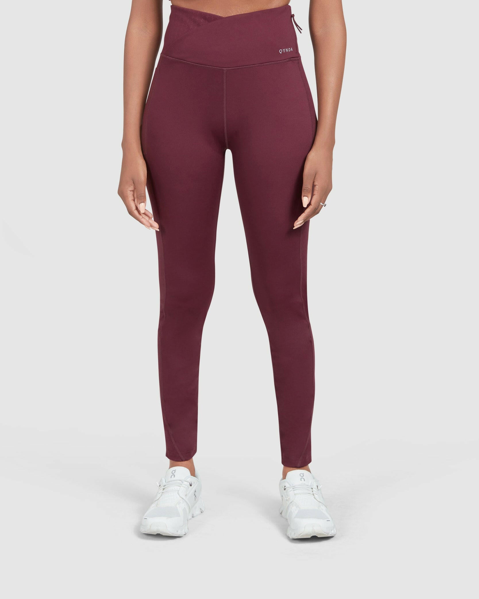 A model wearing Maroon Modest LADINA LEGGINGS by Qynda against a plain background, showcasing the fit and style of athleisure wear.