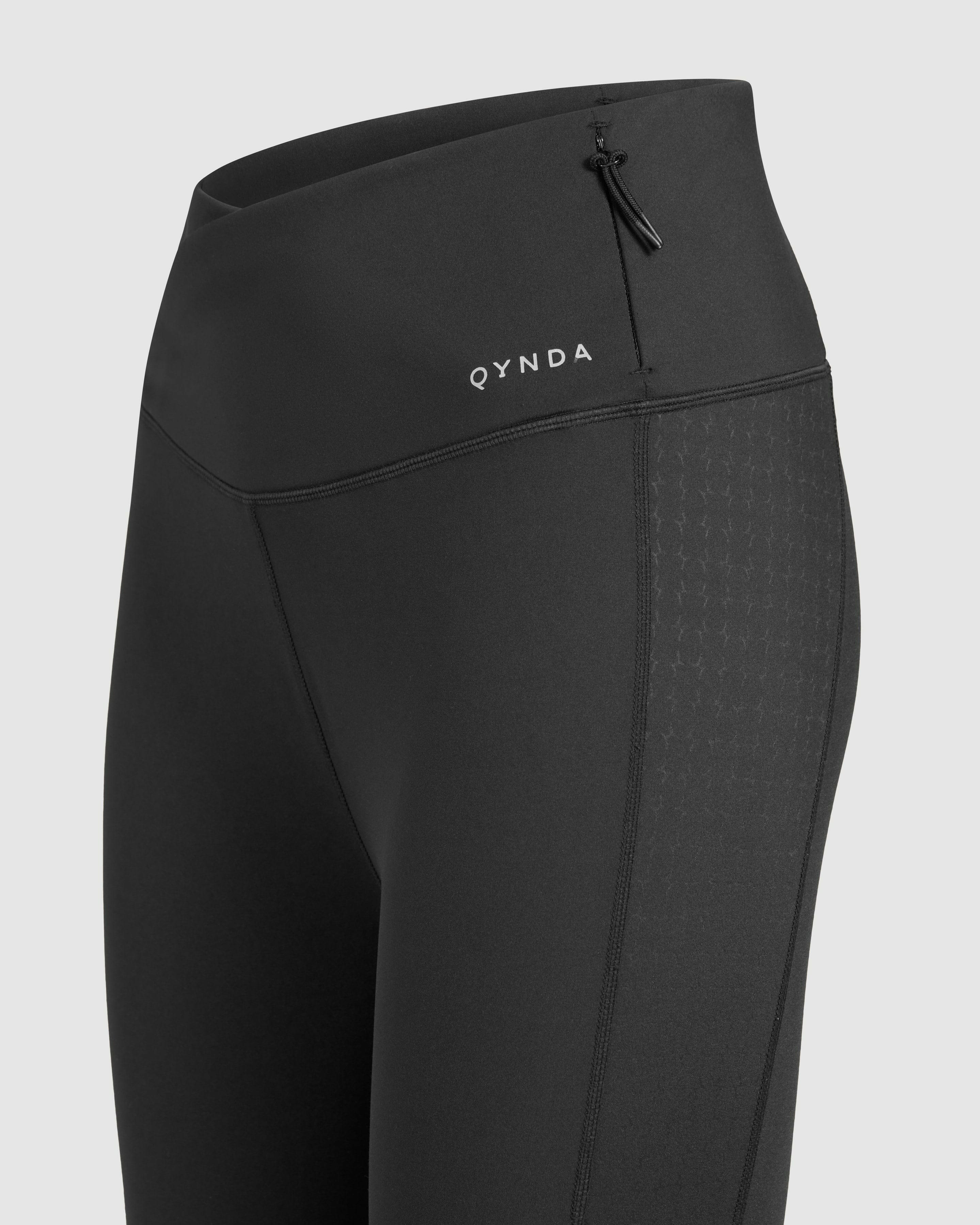 Close-up of a black sports LADINA LEGGINGS featuring a subtle QYNDA brand logo and a drawstring waist detail.