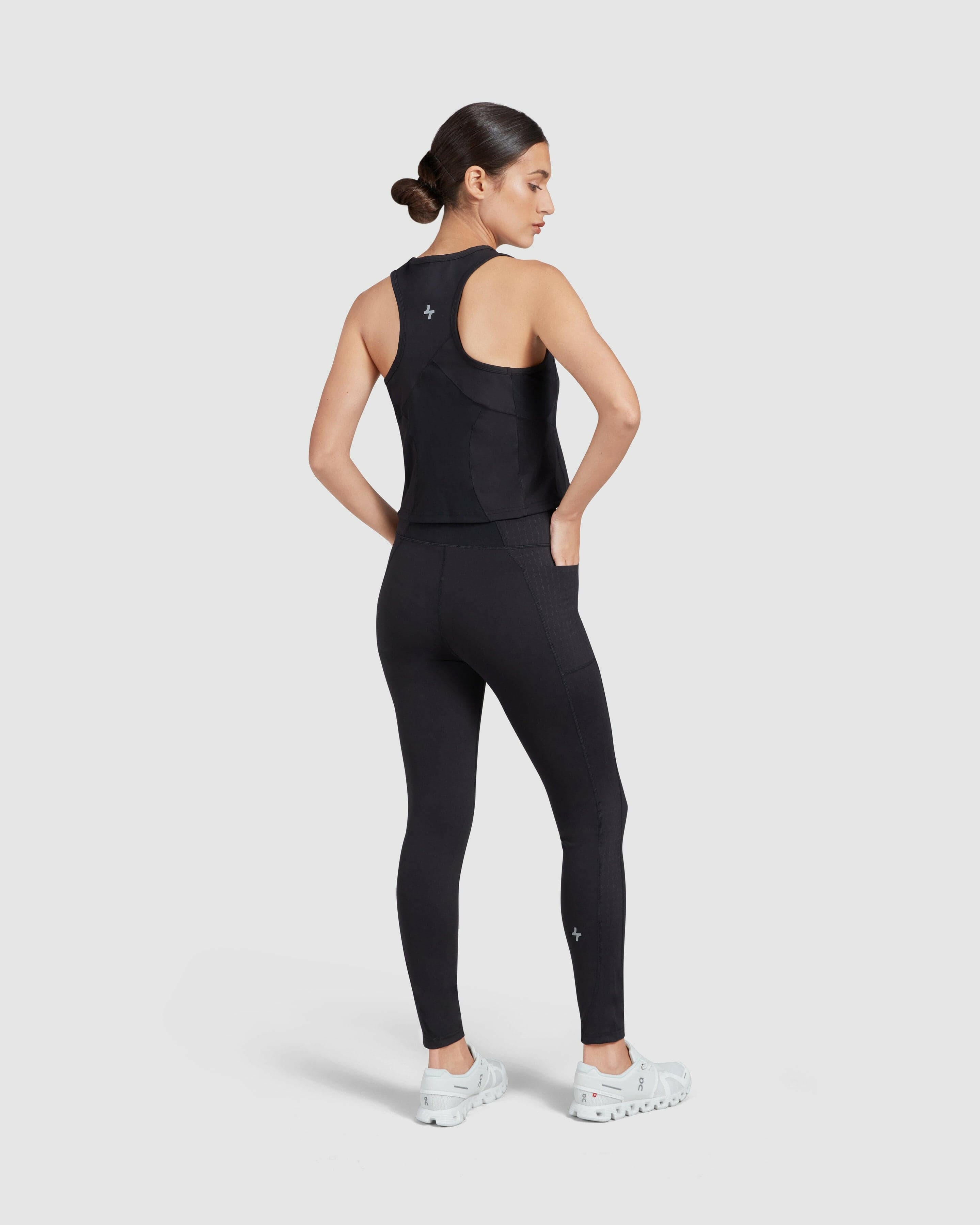  Model in Modest athletic wear posing with her back to the camera, showcasing the fit and design of a better-fitting black tank top and LADINA LEGGINGS set against a white background.
