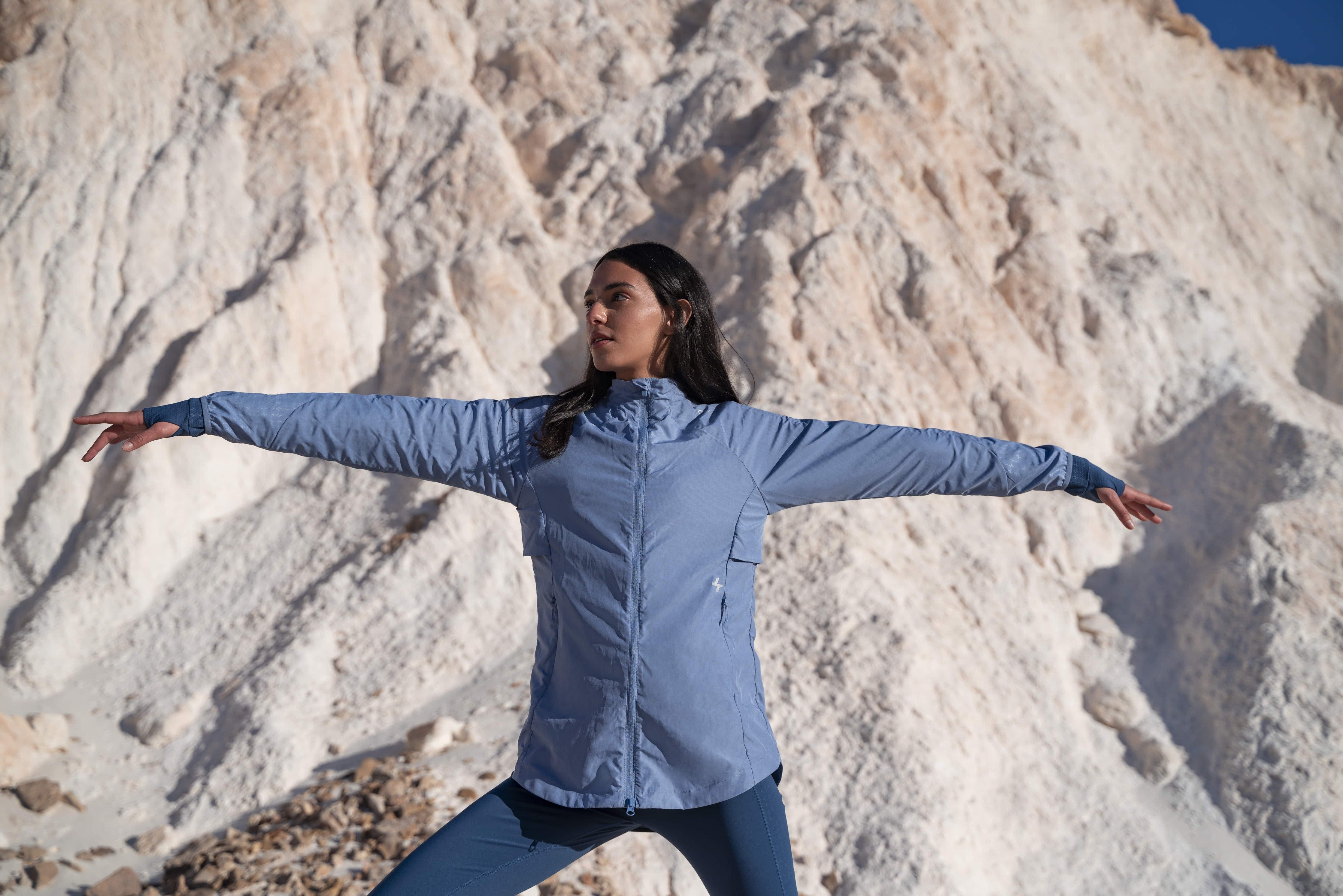 A woman practicing yoga in modest activewear by qynda, with a mountainous backdrop, embodying a sense of balance and tranquility in nature.