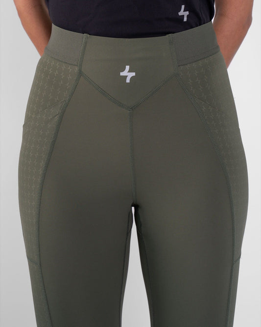 A woman showcasing the Olive modest THABYA LEGGINGS, with a patterned panel and qynda logo.