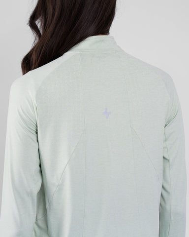 Back view of a model wearing a Sage color, high-neck sleeve shirt ARMA by Qynda.
