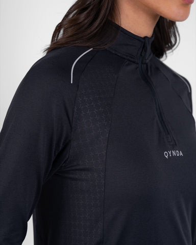 Close-up of a woman wearing a black, high neck long sleeve shirt ARMA by Qynda, featuring a subtle pattern.